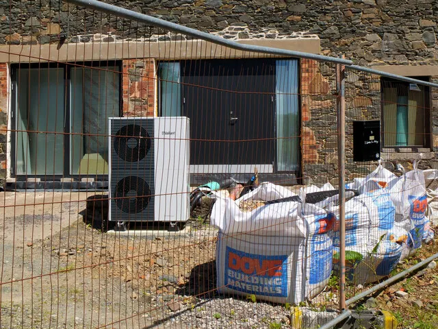 A twin-fan heat pump at a brick house undergoing renovation — back-yard positions in Leicester terraces are usually permitted development if the noise test passes.