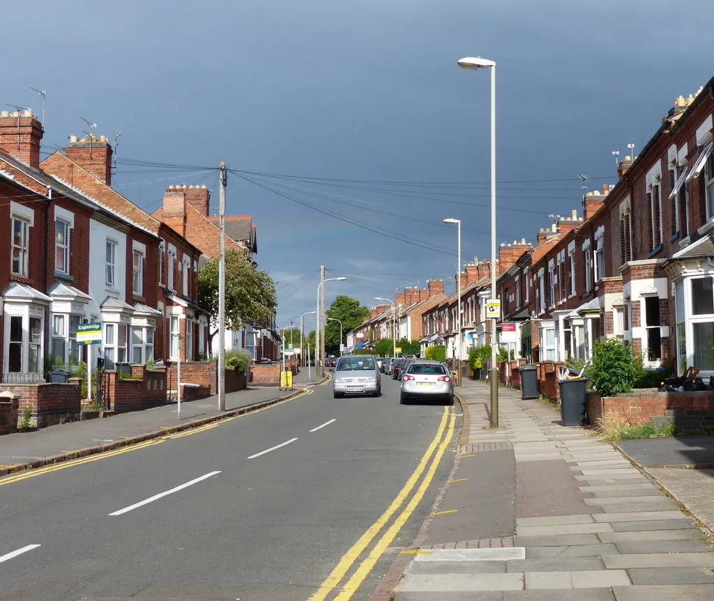 A wide Leicester street lined with bay-window Victorian terraces under a dramatic sky — period housing stock common across Leicester's inner suburbs, including parts of Evington.